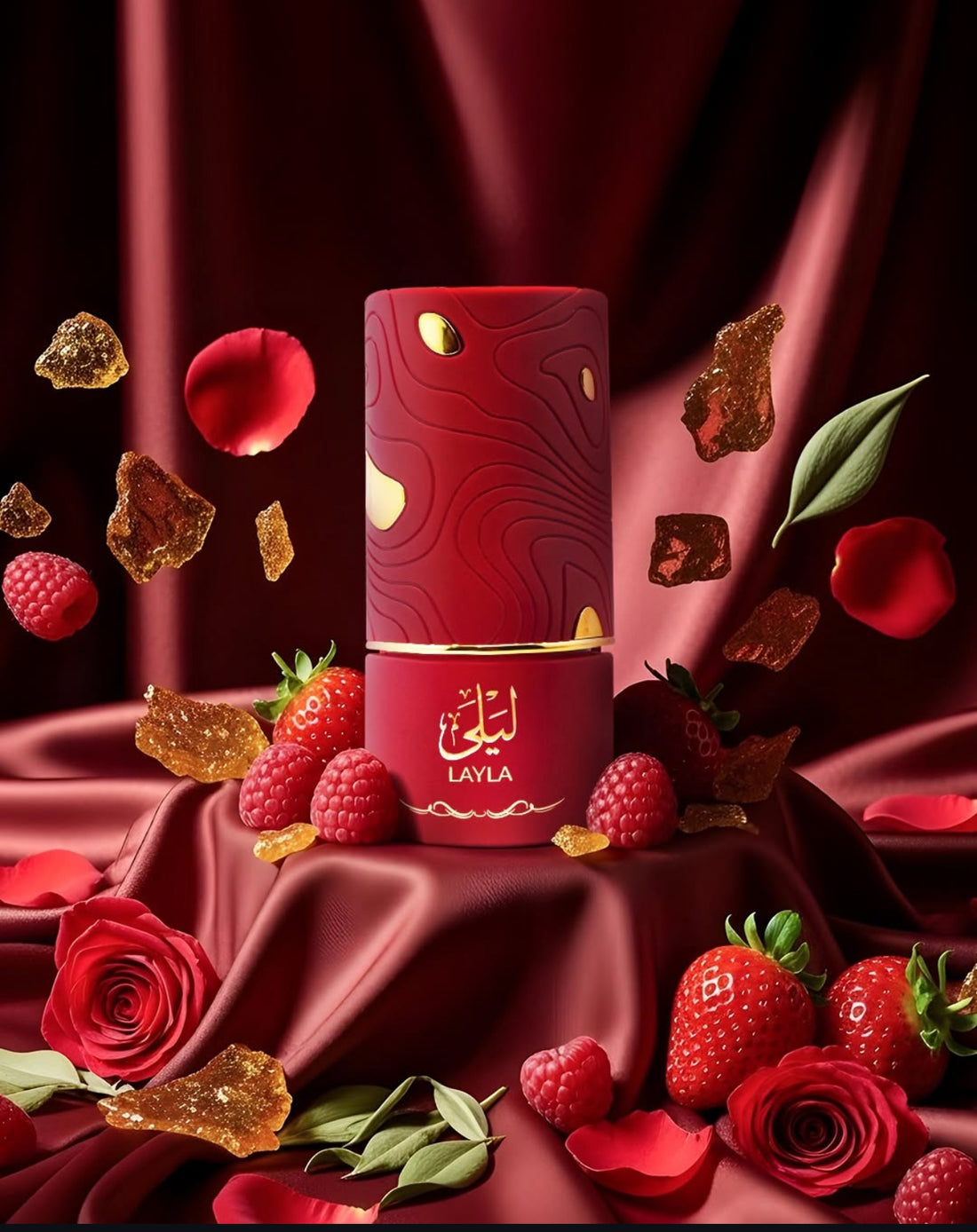 Layla Al Absar EDP 100ml bottle surrounded by strawberries, raspberries, rose petals, and gold accents on a luxurious red fabric.