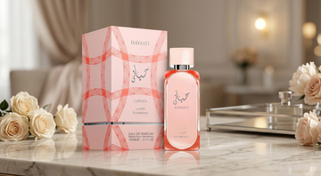 Un flacon et une boîte de HAYAATI Florence Eau De Parfum sur une surface en marbre avec des roses crème.