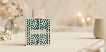 Flacon de parfum Rayhaan dans un étui en dentelle crème élégant sur une surface en marbre avec de douces touches florales.