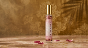 Flacon de parfum Pink Reverie de Maison Maïta sur une surface en marbre rose avec des pétales de rose et un éclairage d'ambiance doux
